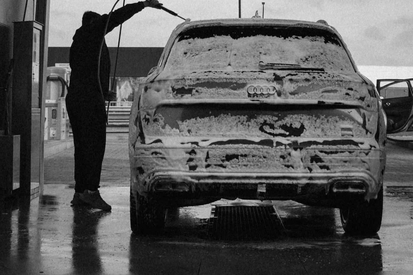 Mobile detailer pressure washing a vehicle covered in foam